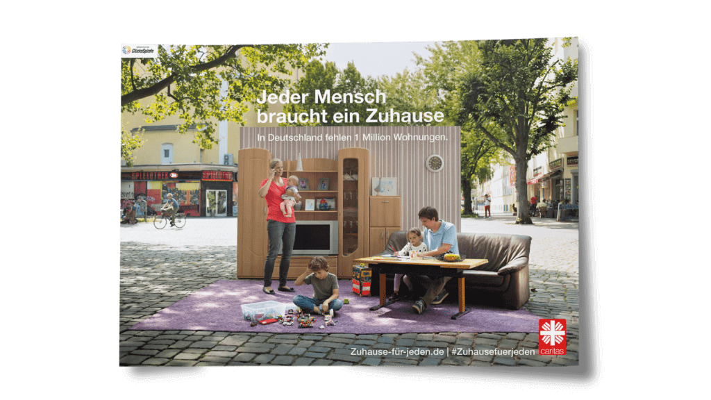 Das Plakat der Kampagne gegen Wohnungsnot für die Caritas von glow zeigt eine Familie in einem auf der Straße aufgestellten Wohnzimmer. Jeder Mensch braucht ein Zuhause.