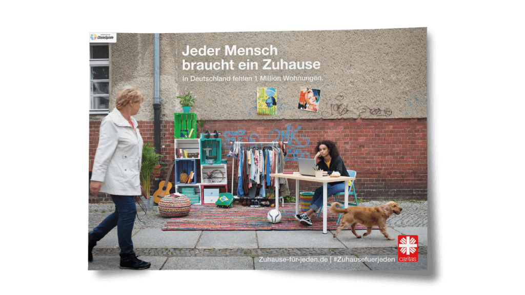 Das Plakat der Kampagne gegen Wohnungsnot für die Caritas von glow zeigt ein Mädchen in einem auf der Straße aufgestellten Zimmer. Jeder Mensch braucht ein Zuhause.